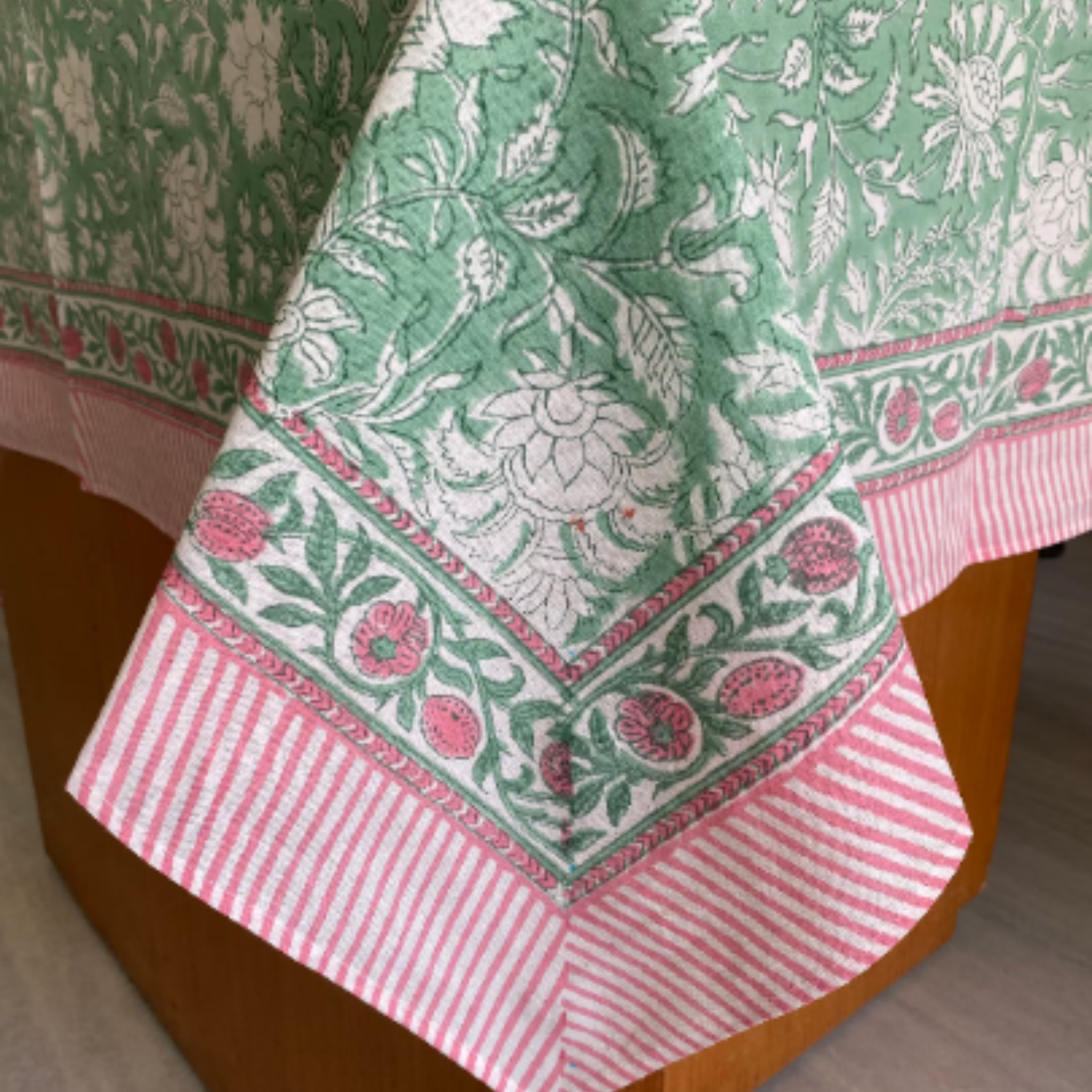 Green and pink floral patterned tablecloth on a wooden table