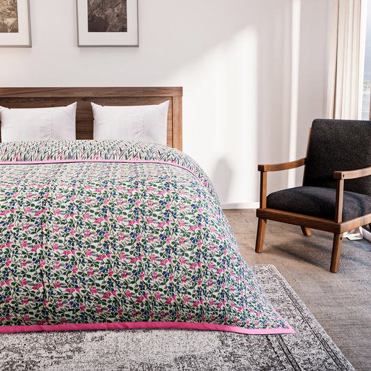 Bed with floral quilt in a bedroom setting with a chair and artwork on the wall.
