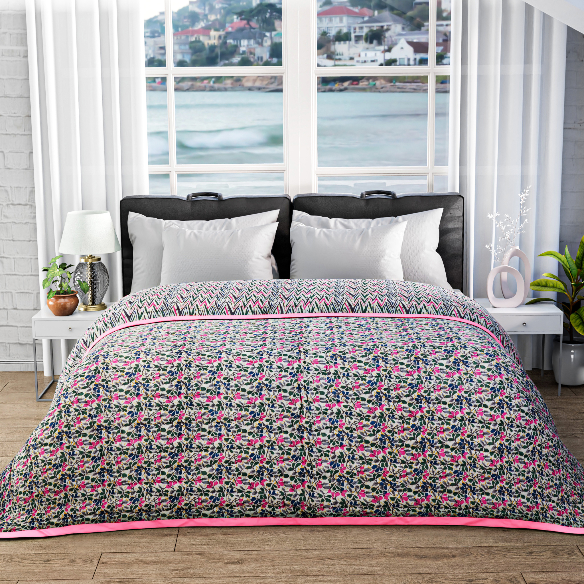 Bed with floral patterned comforter in a room with large windows showing a waterfront view.