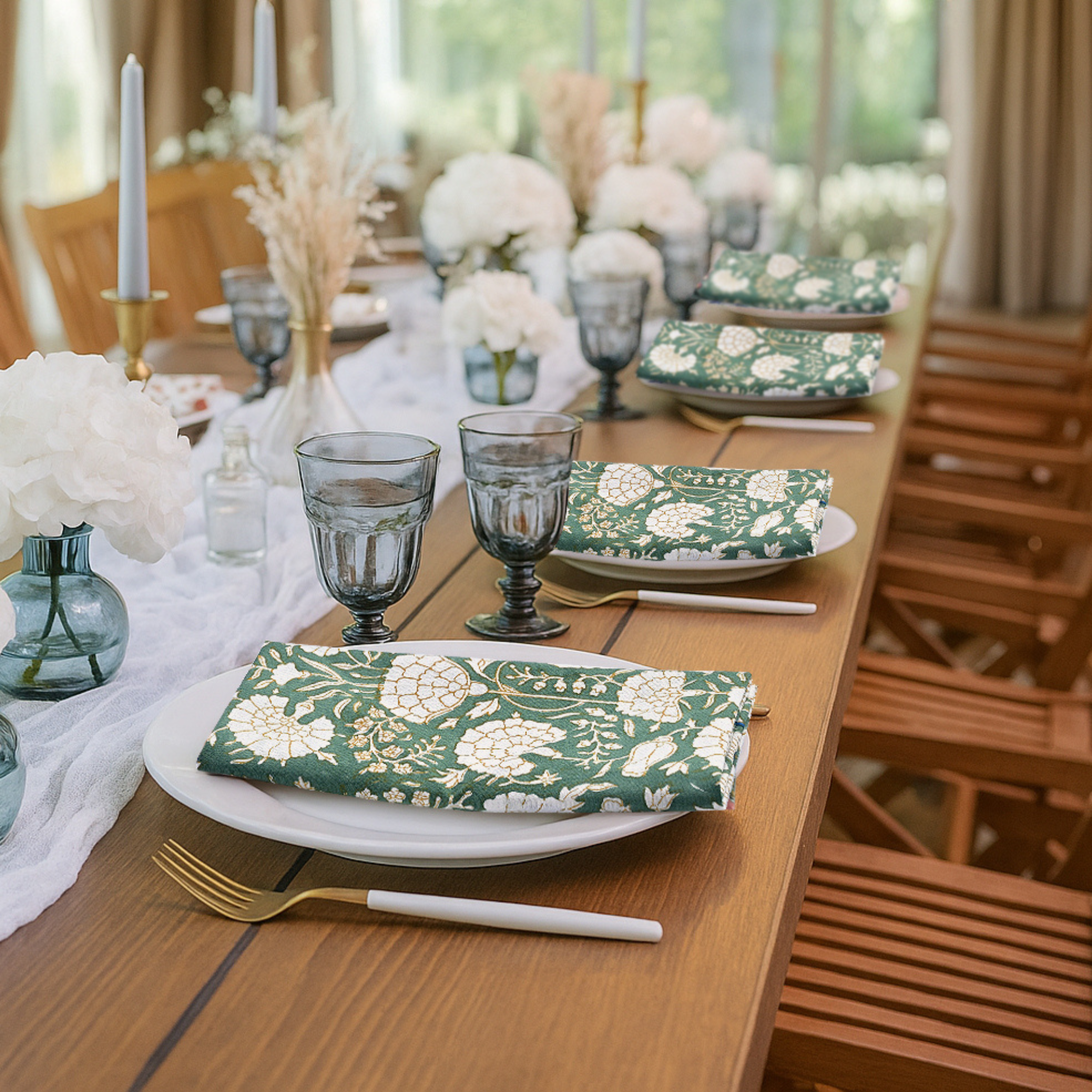 Elegant table setting with green floral plates and napkins in a bright room.