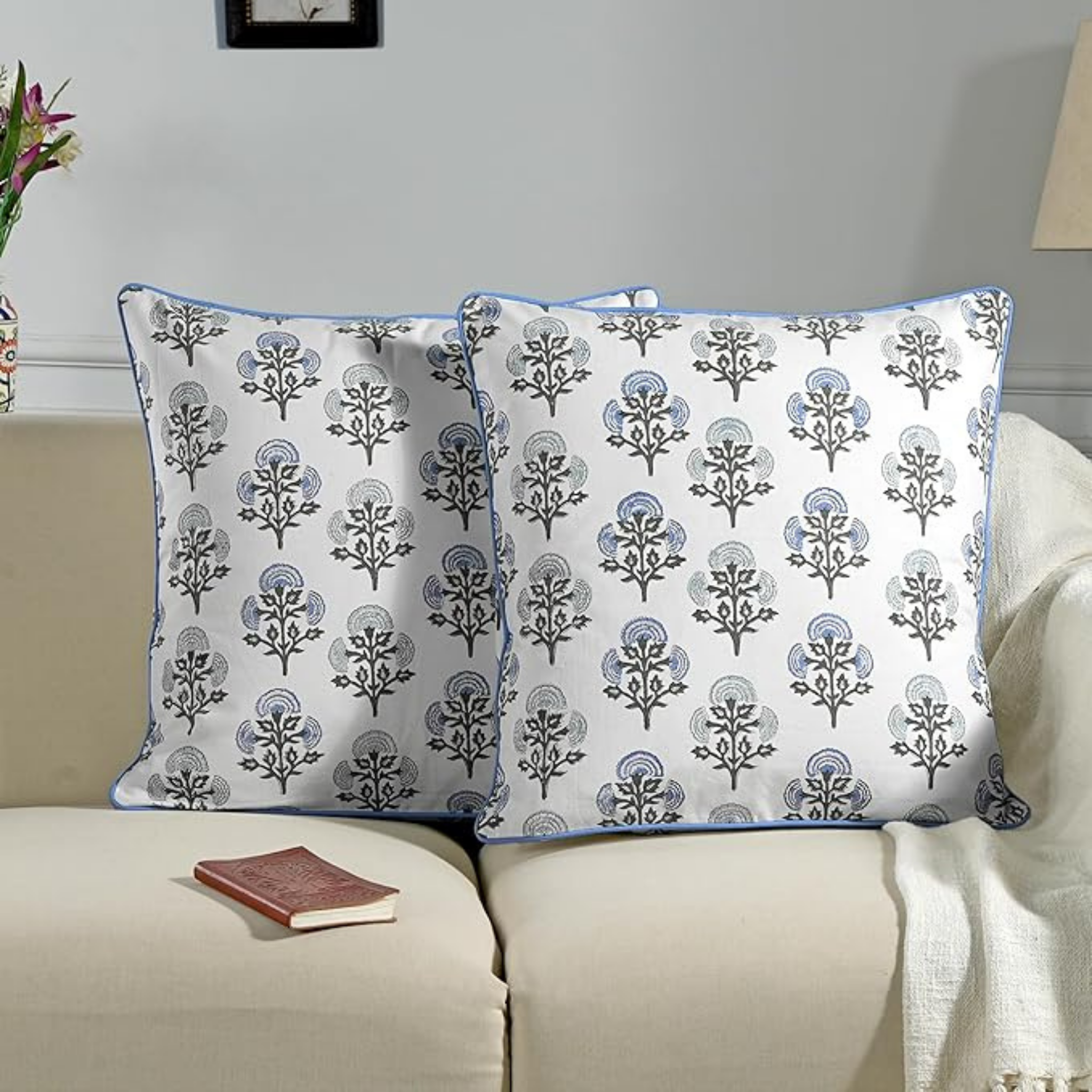 Two decorative pillows with a floral pattern on a beige sofa.