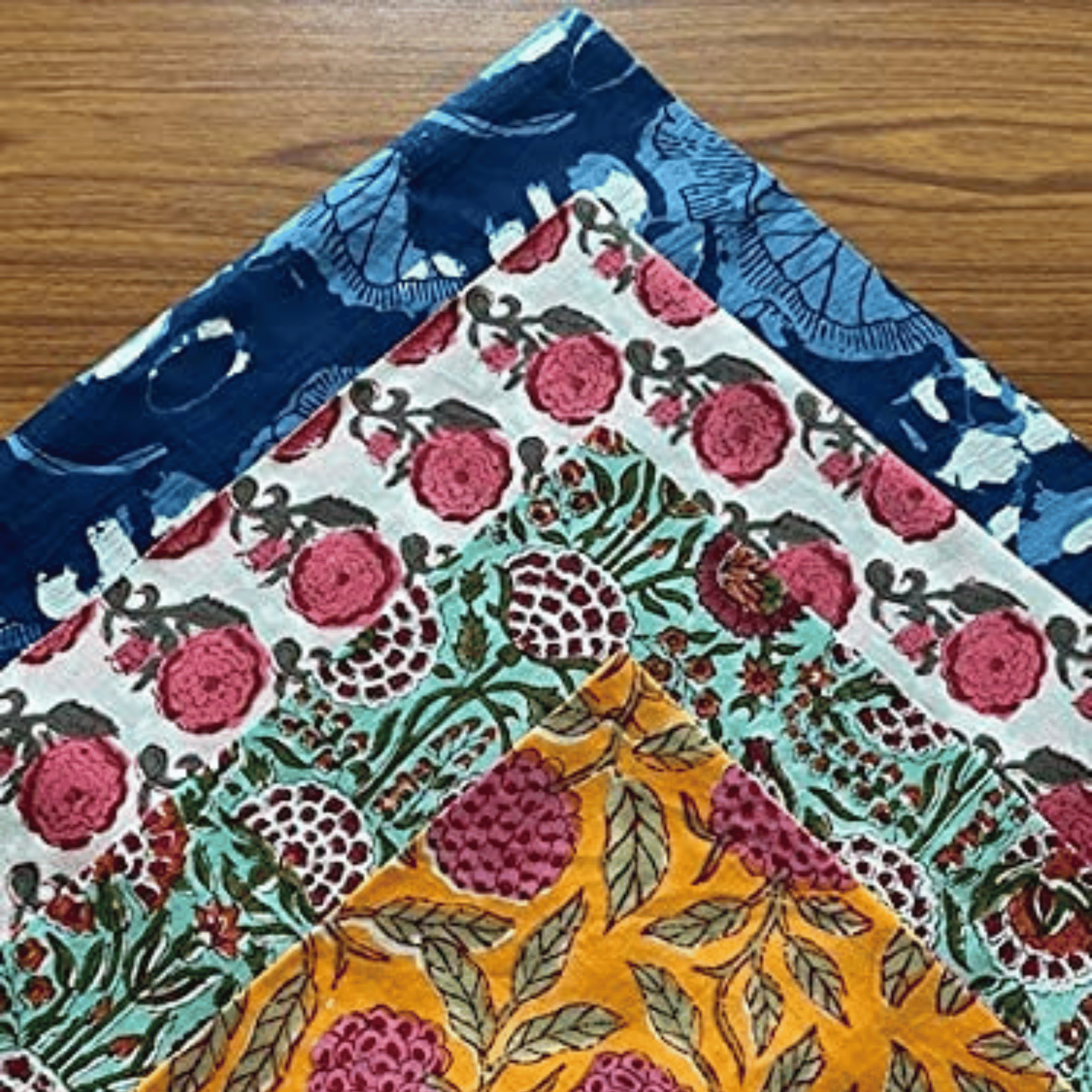 Three pieces of fabric with floral patterns on a wooden surface