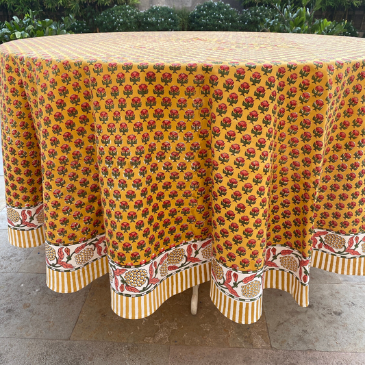 Round table with a yellow floral patterned tablecloth on a stone surface.