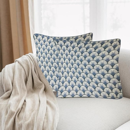 Two blue patterned pillows on a light-colored sofa with a beige blanket.