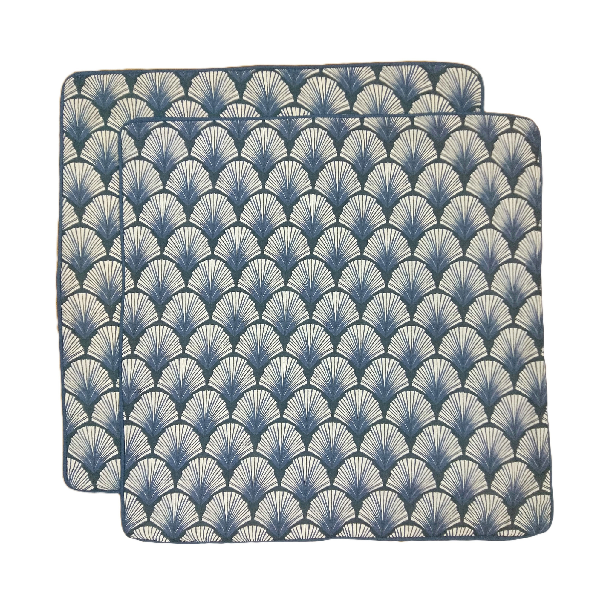 Two blue and white patterned placemats on a white background