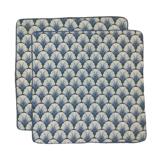 Two blue and white patterned placemats on a white background