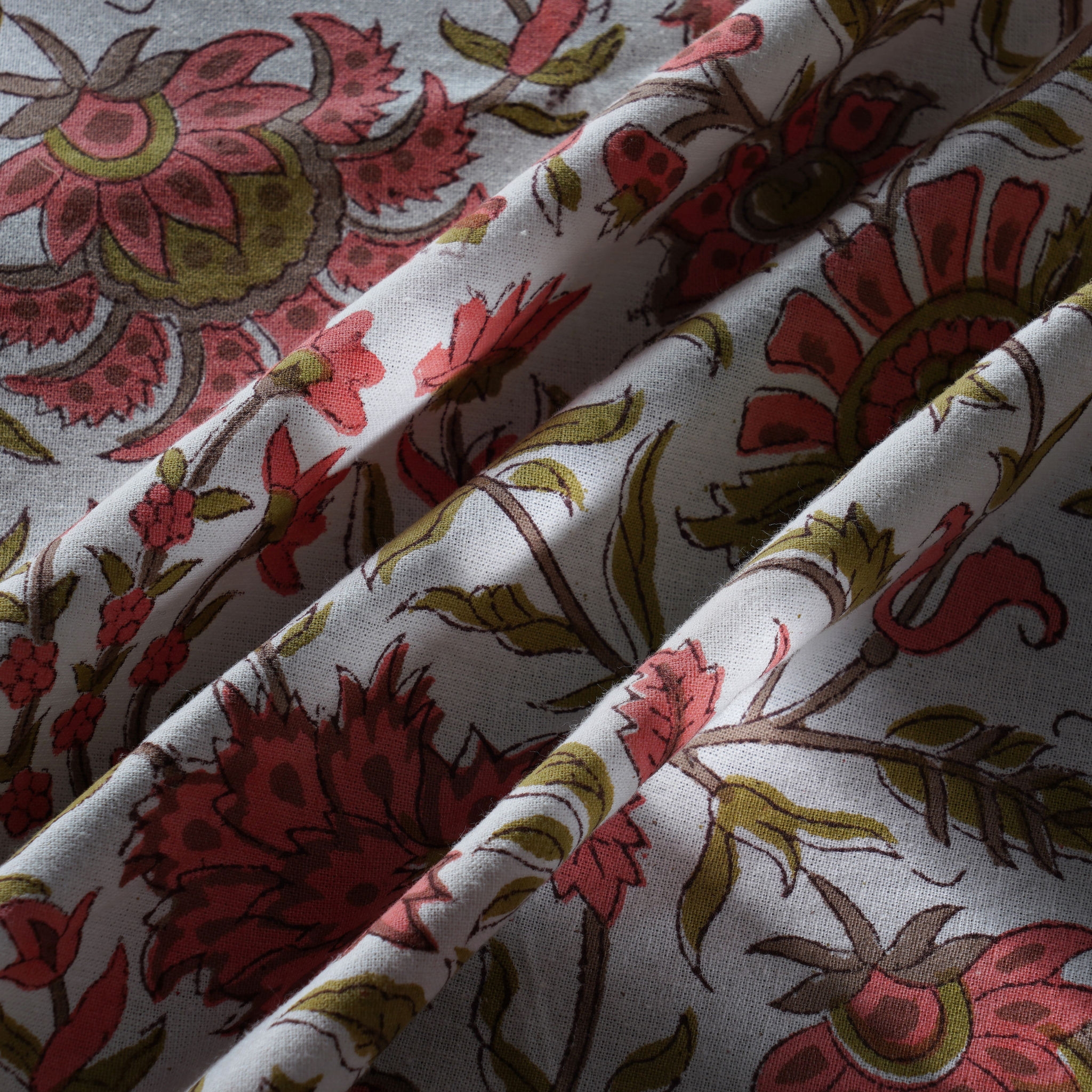 Close-up of floral patterned fabric with red, green, and brown colors.