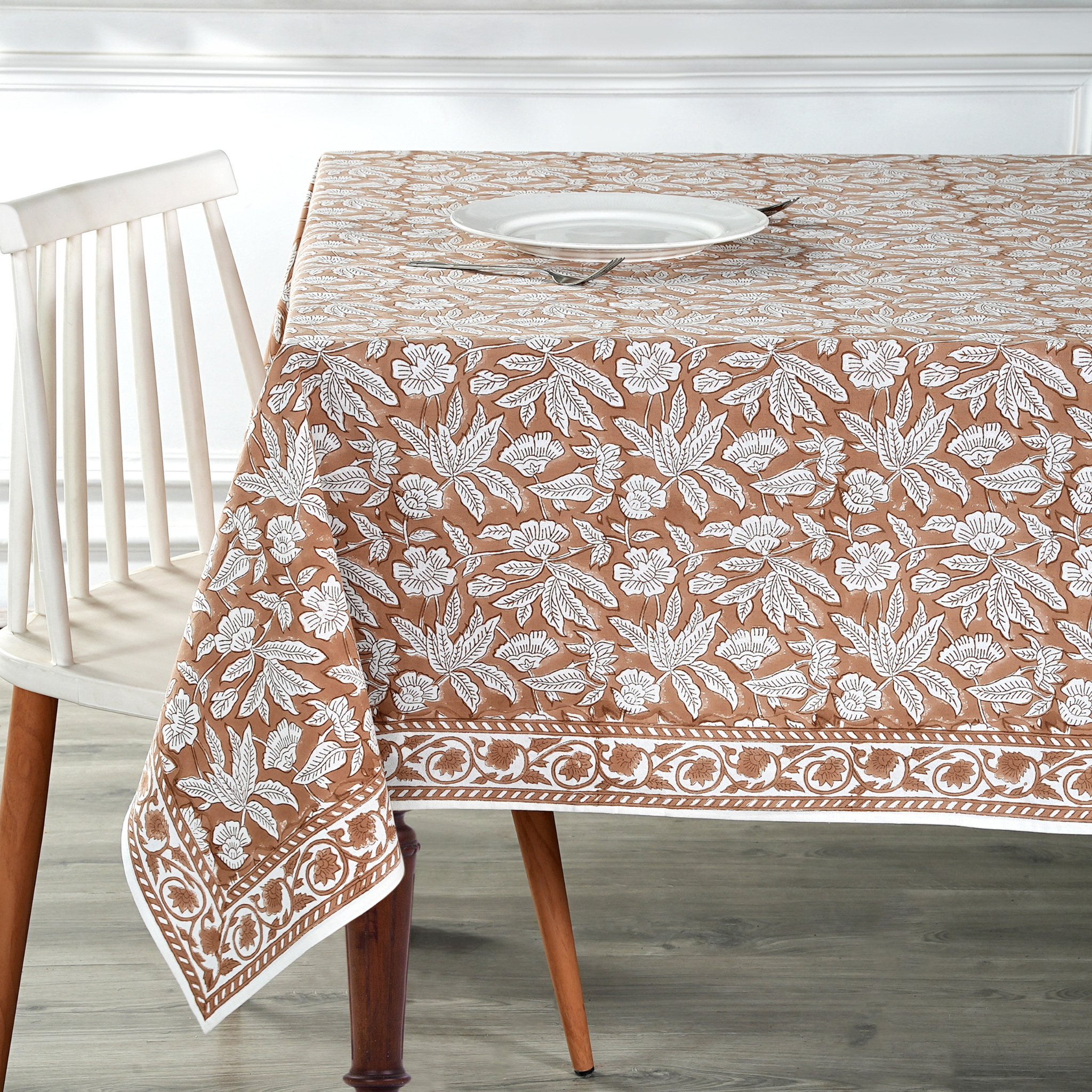 Tablecloth with floral pattern on a wooden table and chair.
