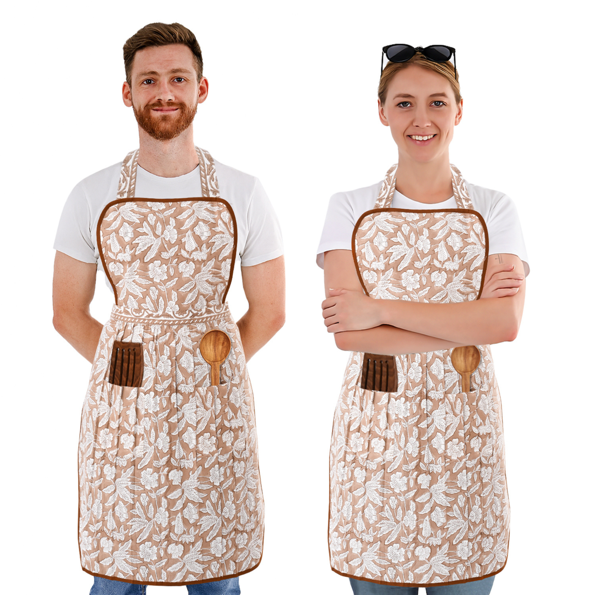 Two people wearing floral aprons with wooden hooks on a white background