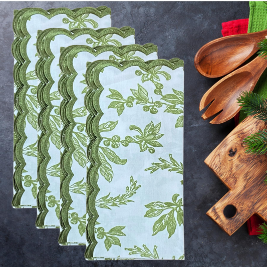 Set of green leaf-patterned napkins on a dark surface with wooden cutlery and board.