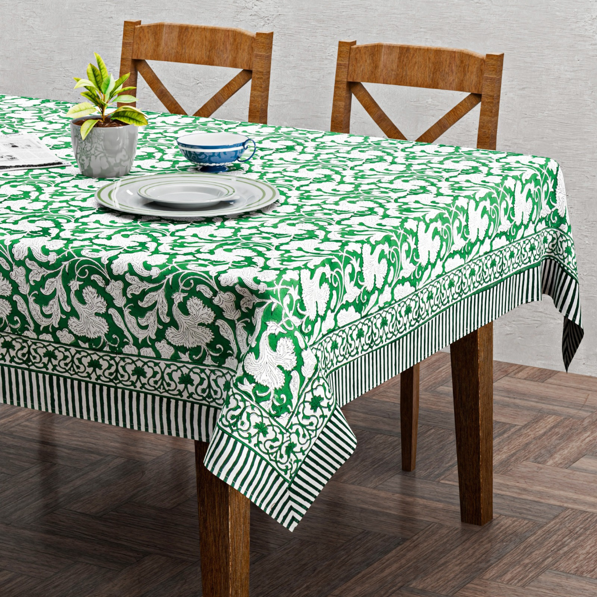 Table with a green and white patterned tablecloth on wooden chairs.