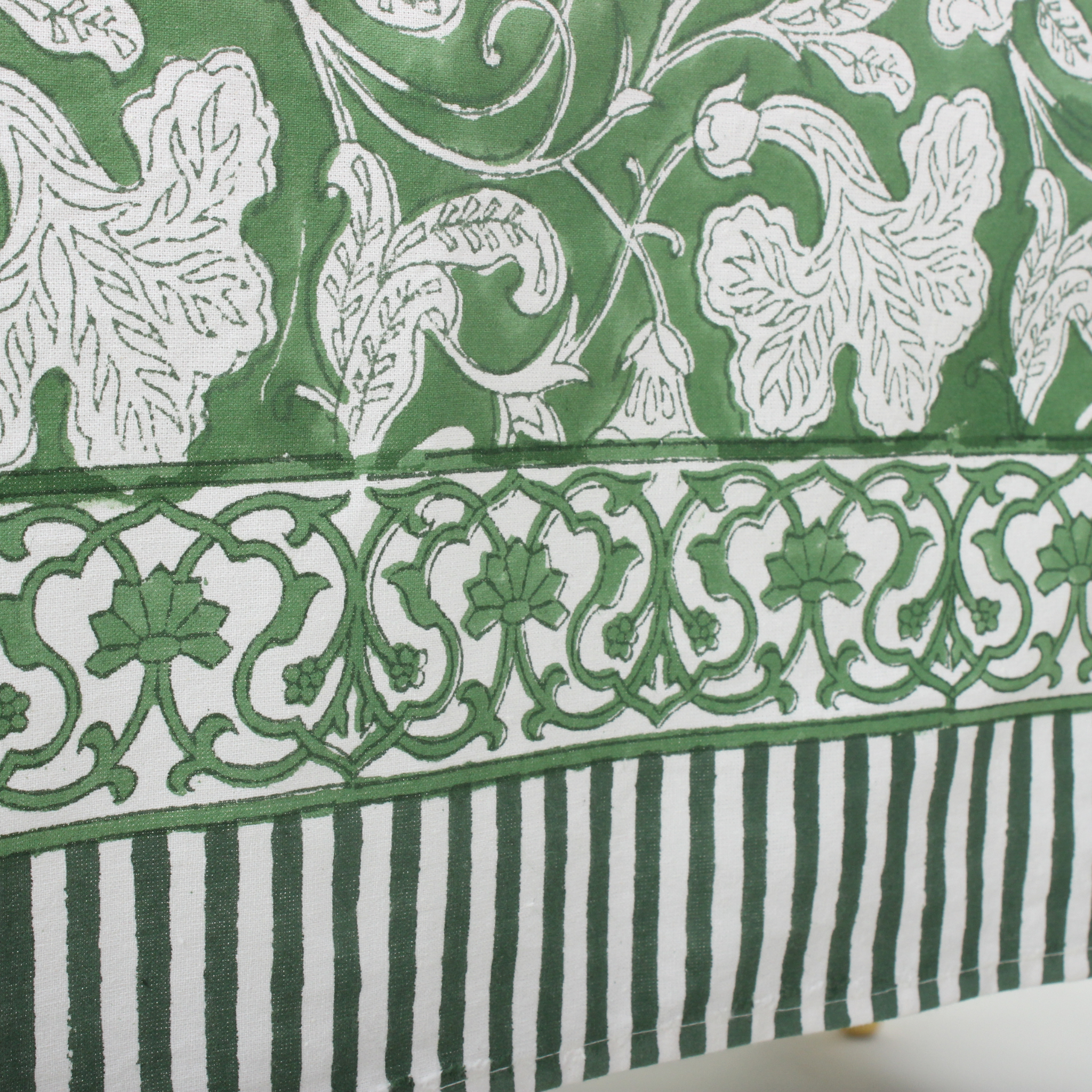 Green and white patterned fabric with floral and striped designs.