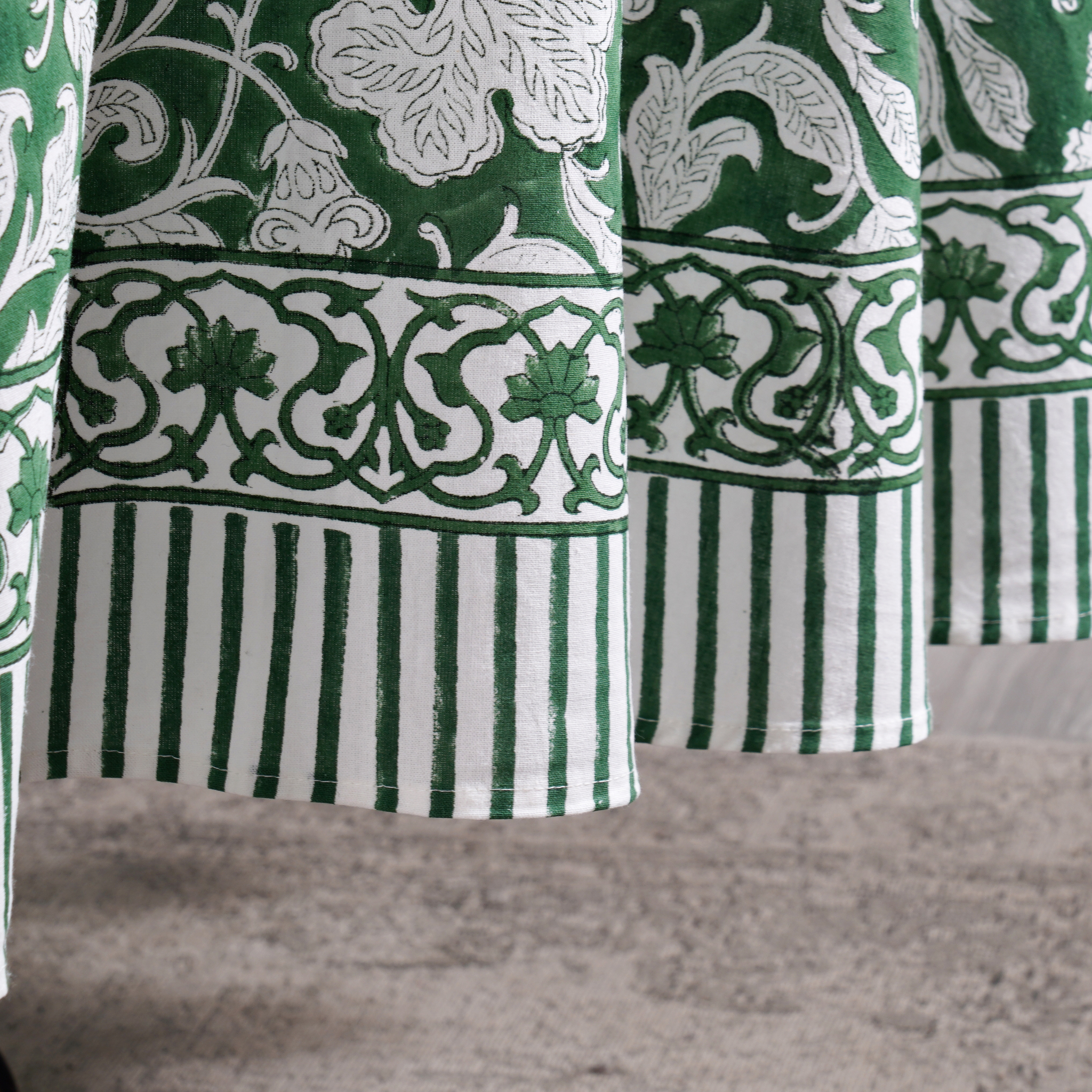 Green and white patterned fabric with floral and striped designs.