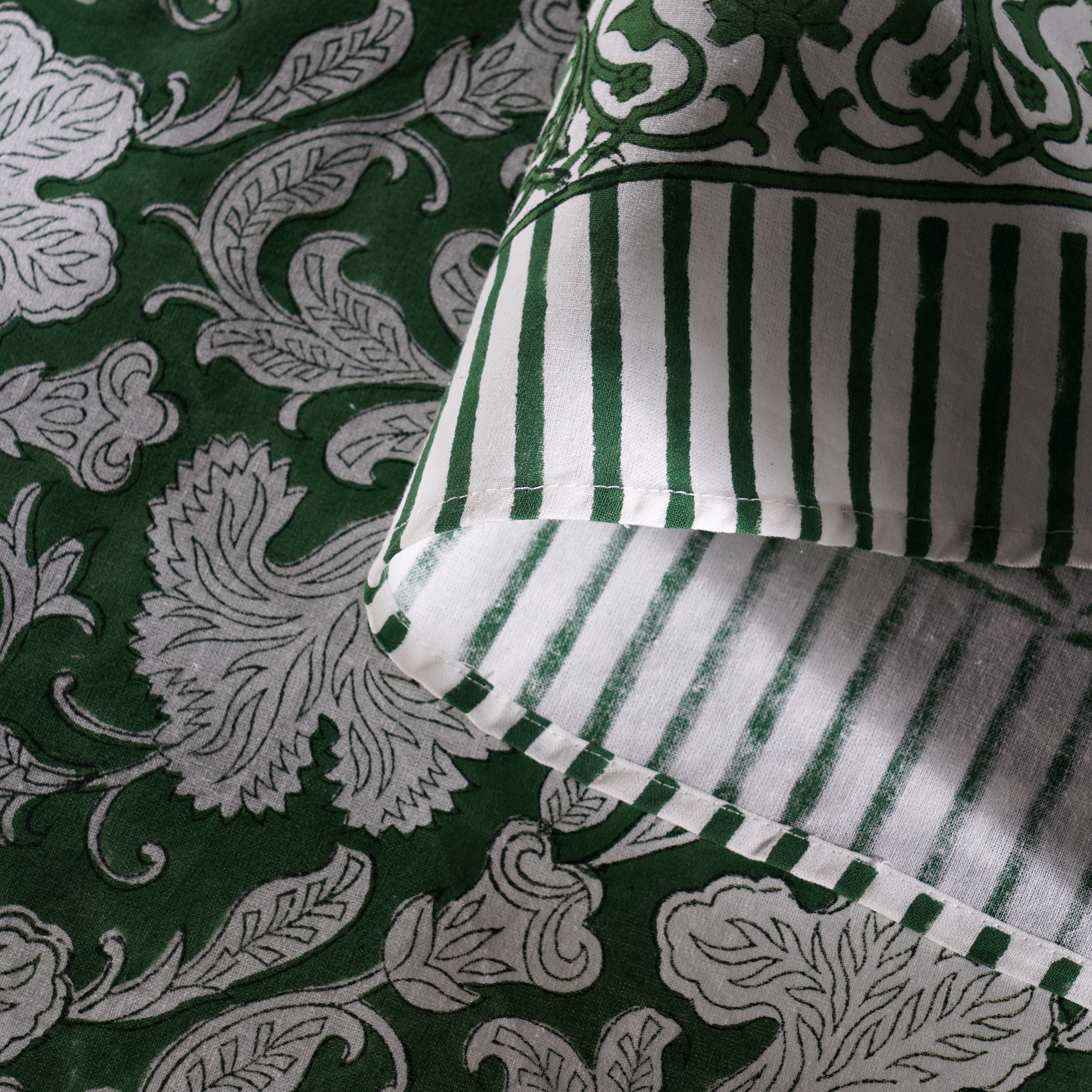 Green and white patterned fabric with a striped pillow