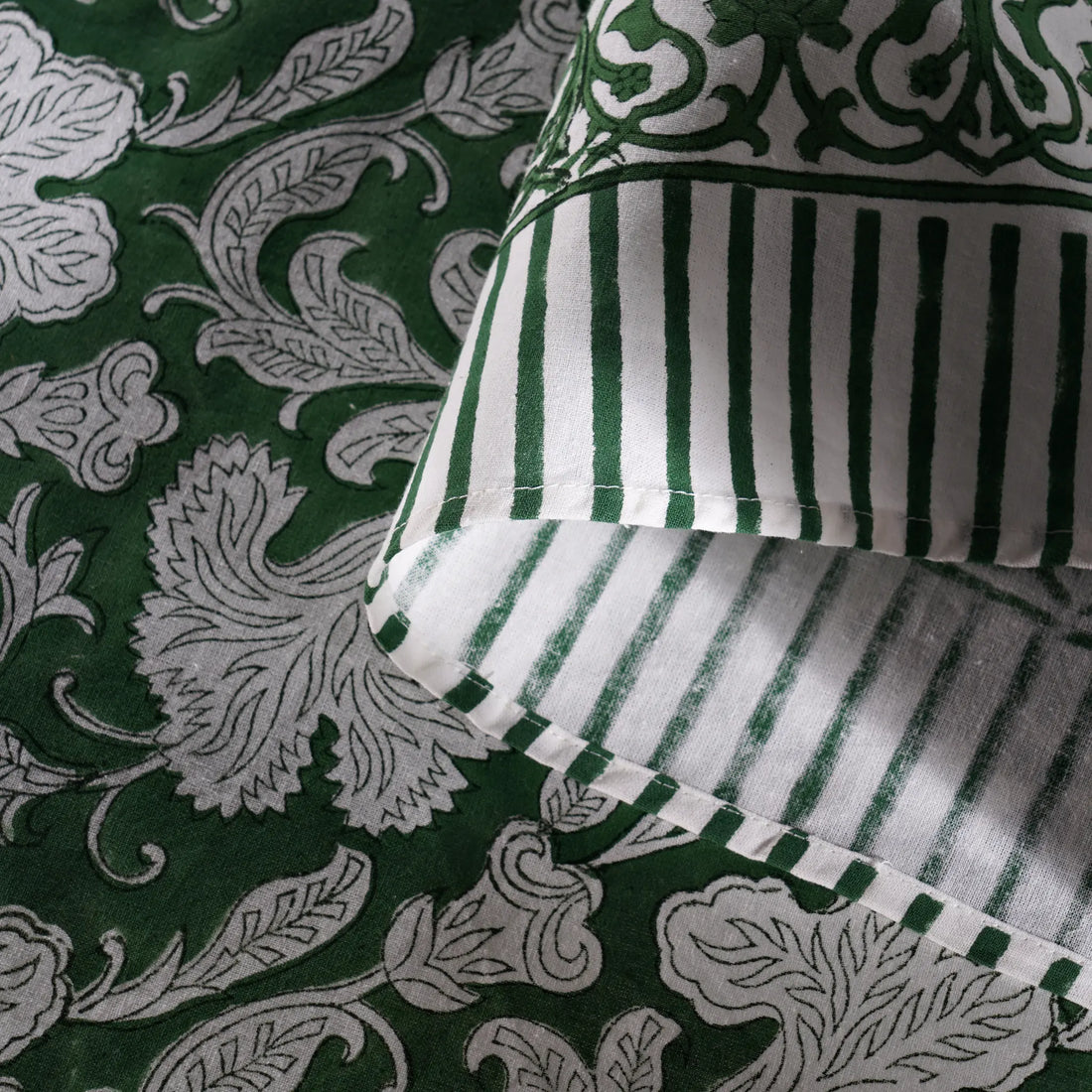Green and white patterned fabric with a striped pillow