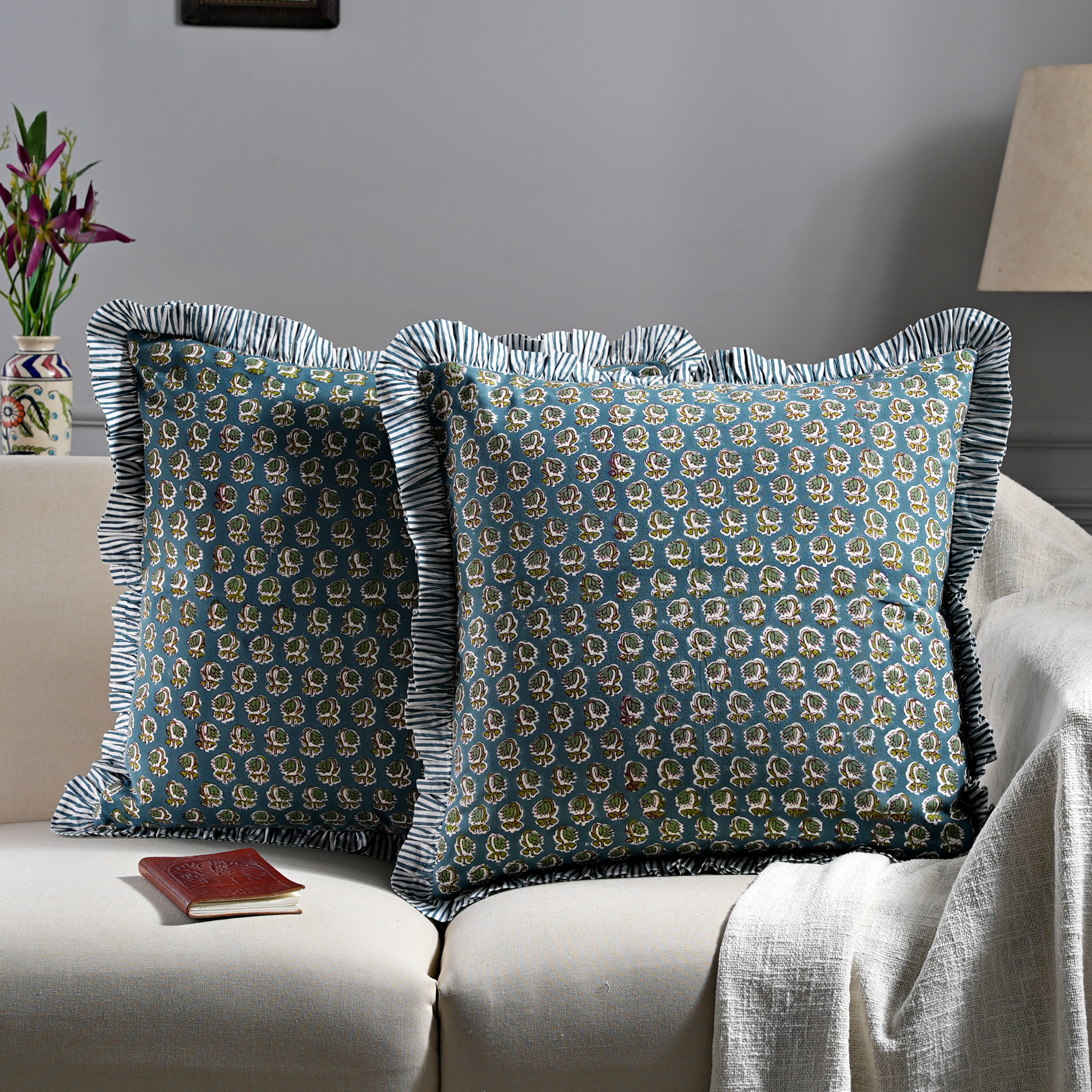 Decorative pillows with a blue and gold pattern on a beige sofa.