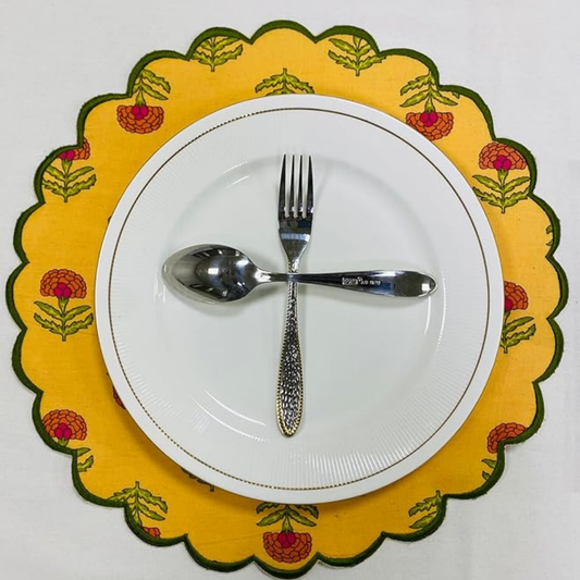 White plate with silver fork and spoon on a yellow floral placemat