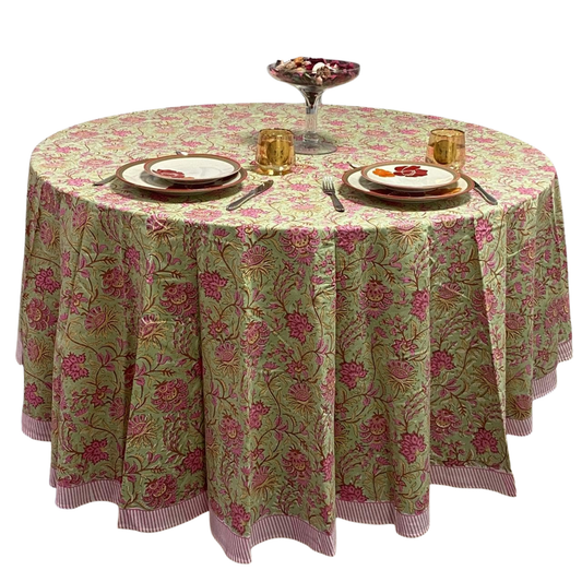Round table with floral patterned tablecloth, plates, and cutlery on a white background