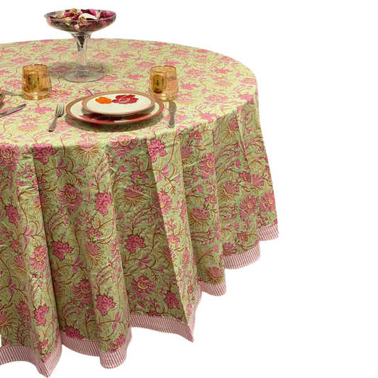 Round table with a floral tablecloth, plates, and glasses on a white background