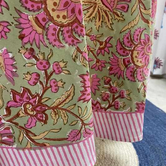 Close-up of a fabric with pink and brown floral pattern on a green background.