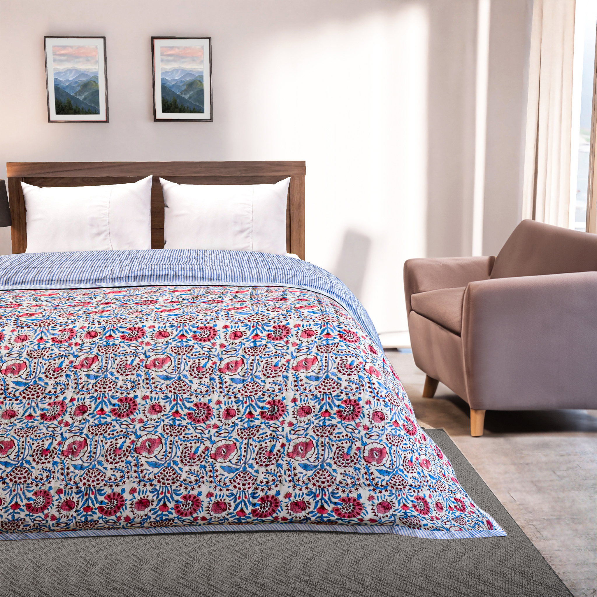 Bedroom with floral-patterned comforter on a bed, armchair, and framed pictures on the wall.