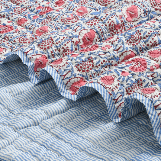 Floral quilt with red and white pattern on a blue striped bedspread