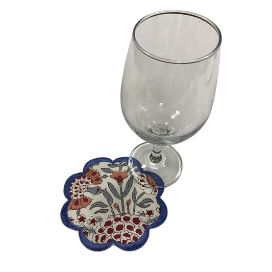 Decorative coaster with floral pattern next to a clear glass on a white background