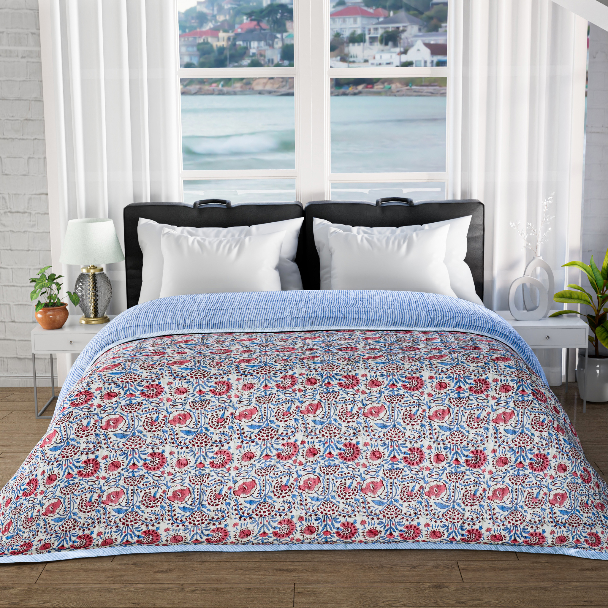 Floral patterned comforter on a bed with a window view of water and buildings.