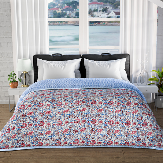 Floral patterned comforter on a bed with a window view of water and buildings.