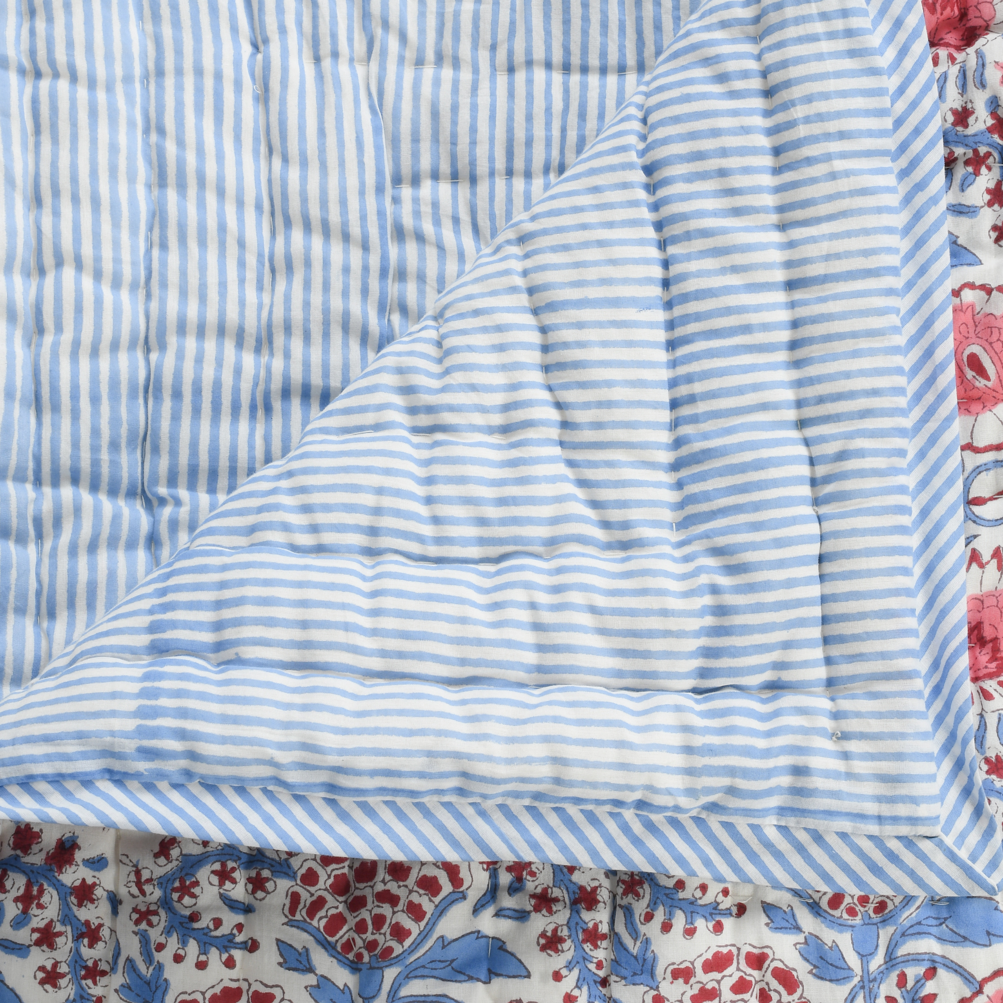 Close-up of a quilt with blue and white striped pattern and floral border