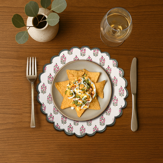 Dinner setting with a plate of nachos, a glass of wine, fork, and knife on a wooden table.