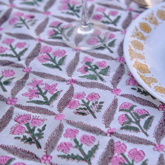 Tablecloth with floral pattern, glass, and plate on a table.
