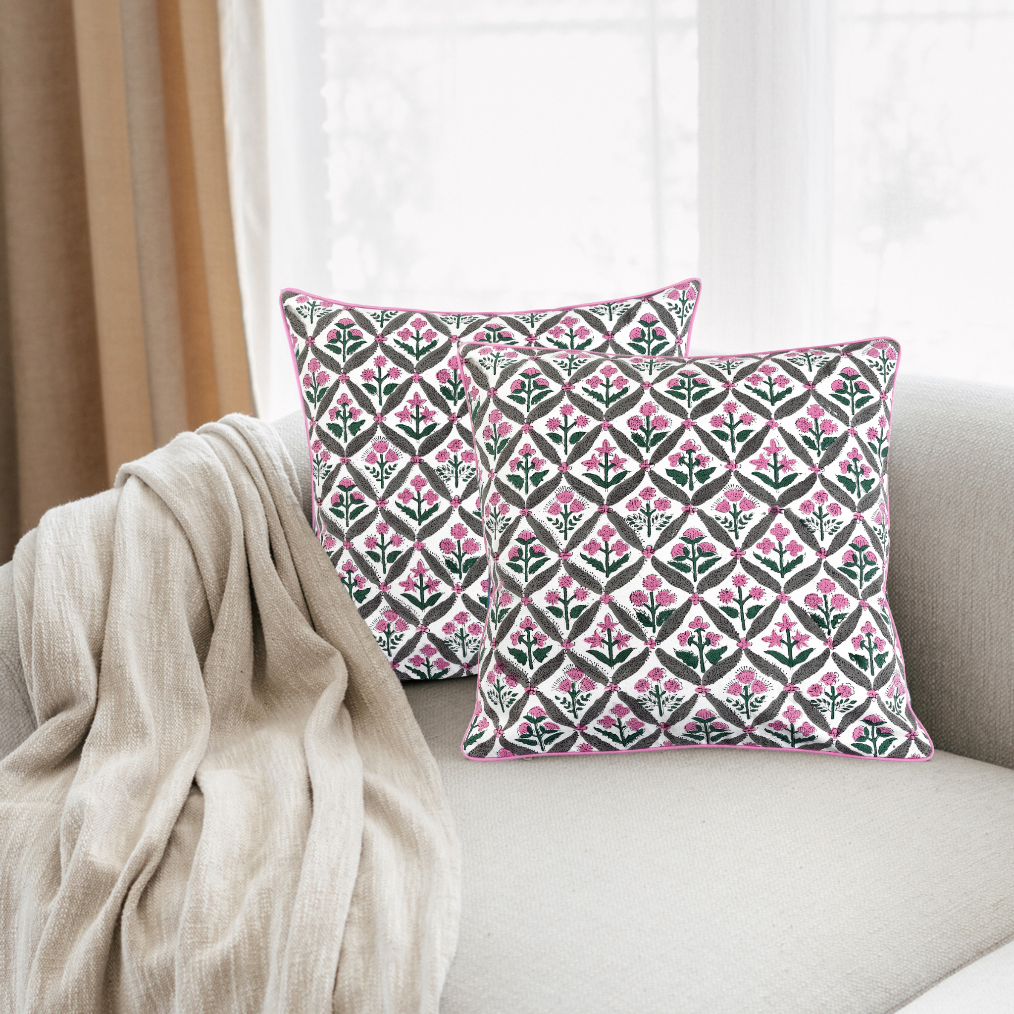 Decorative pillows with a pink and green pattern on a beige sofa.