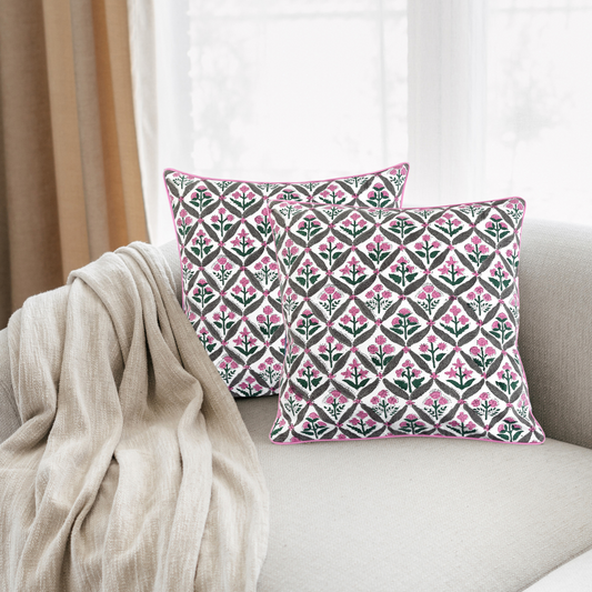 Decorative pillows with a pink and green pattern on a beige sofa.