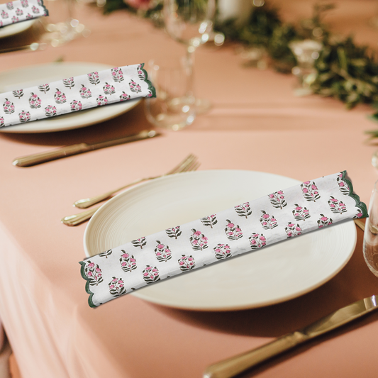 Table setting with floral-patterned napkins on a pink tablecloth.