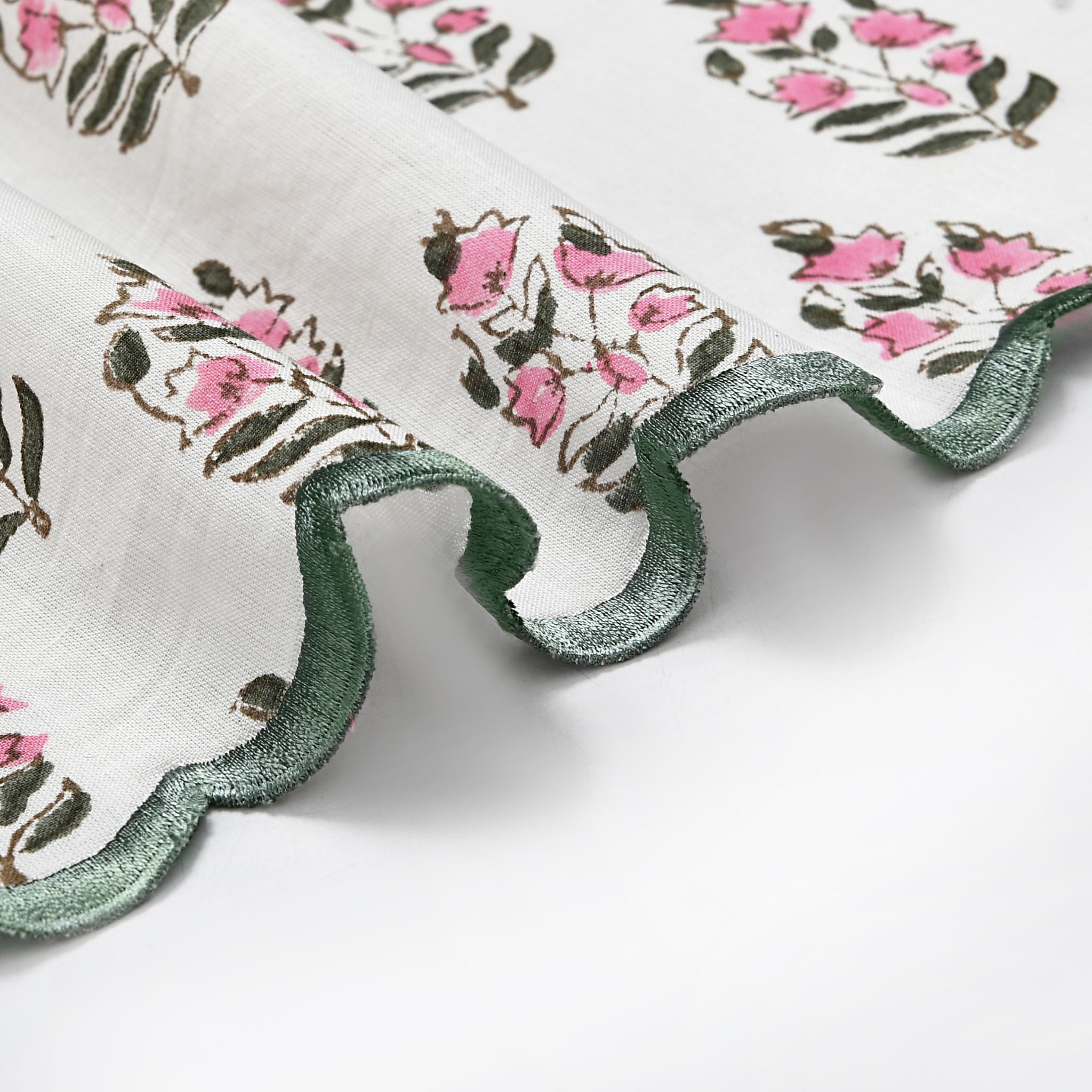 Floral embroidered fabric with pink flowers and green leaves on a white background