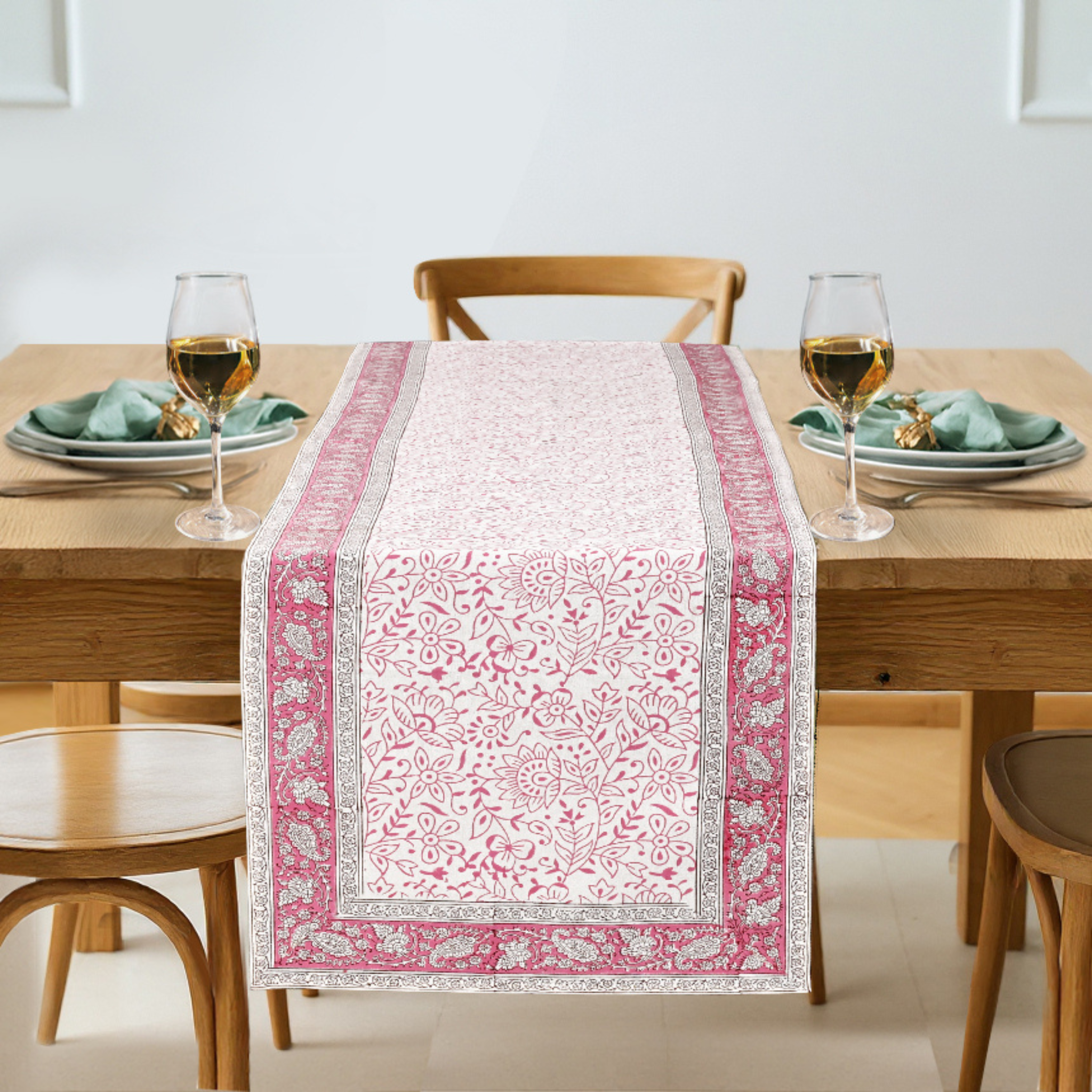 Table setting with a pink and white patterned table runner on a wooden table.