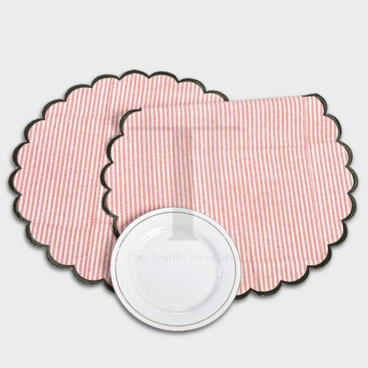 Set of pink striped placemats with scalloped edge on a white background