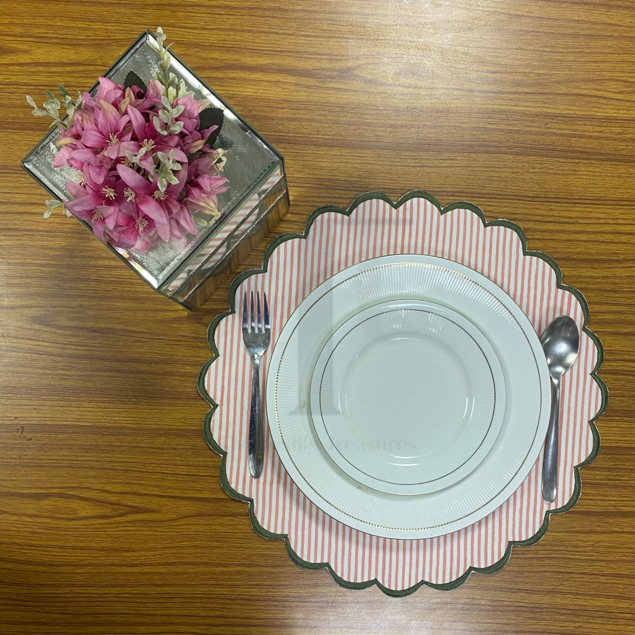 Dinner setting with plates, cutlery, and a decorative plate on a wooden table.