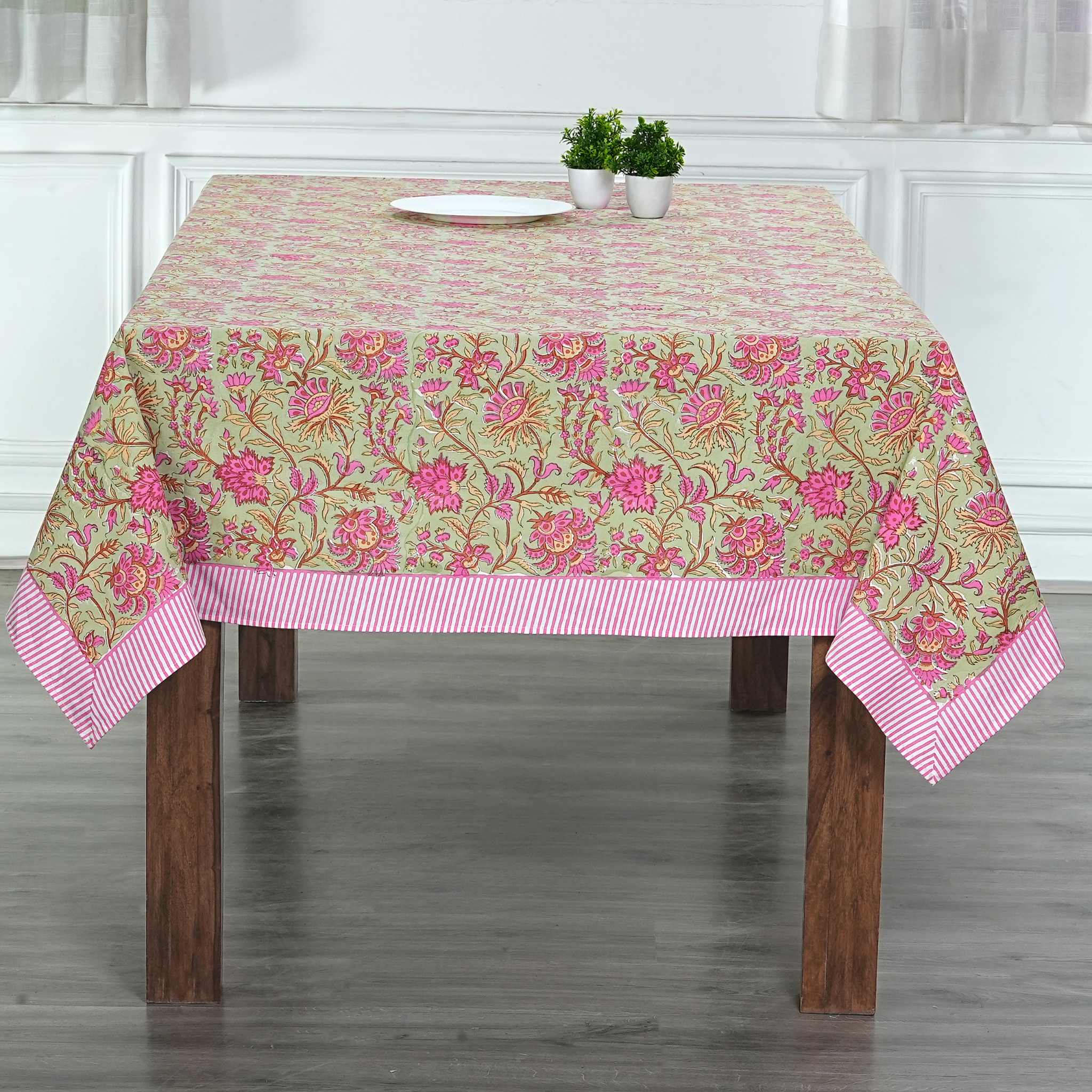 Tablecloth with floral pattern on a wooden table in a room.