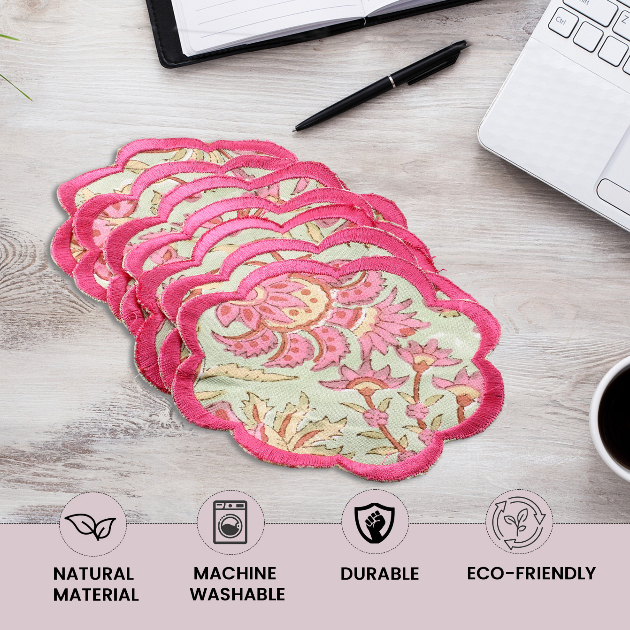 Stack of floral reusable pads on a desk with laptop, pen, and coffee cup.