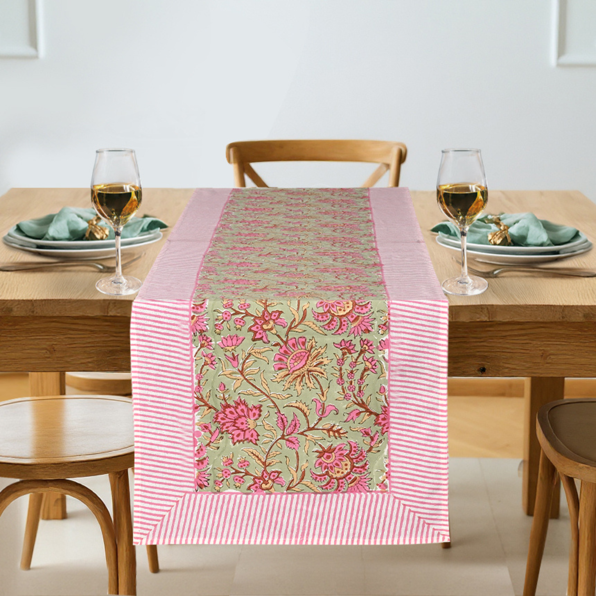Dining table set with a floral table runner, glasses, and plates.