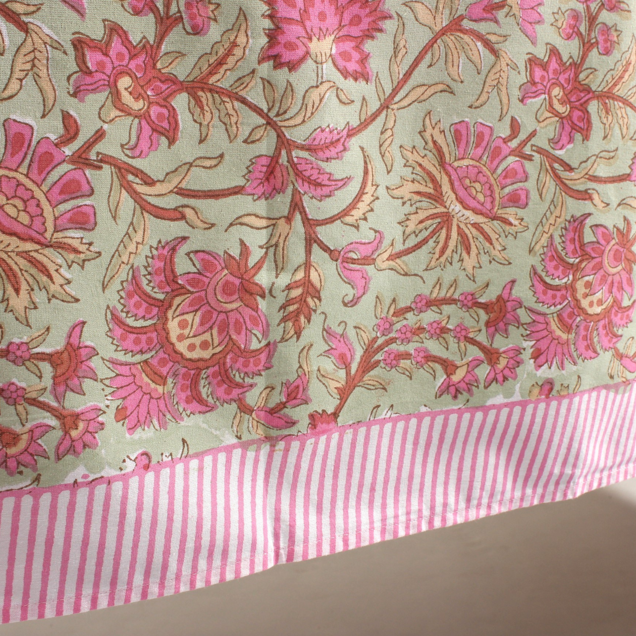 Floral fabric with pink and red flowers on a light background, featuring a pink and white striped border.