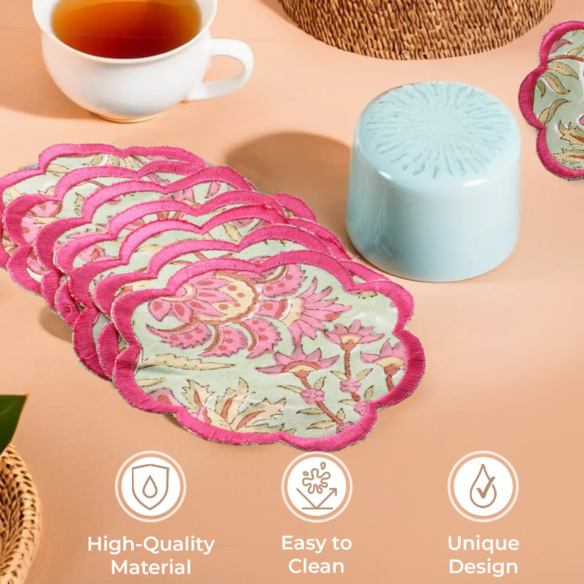 Set of floral coasters with a cup of tea and decorative items on a table.