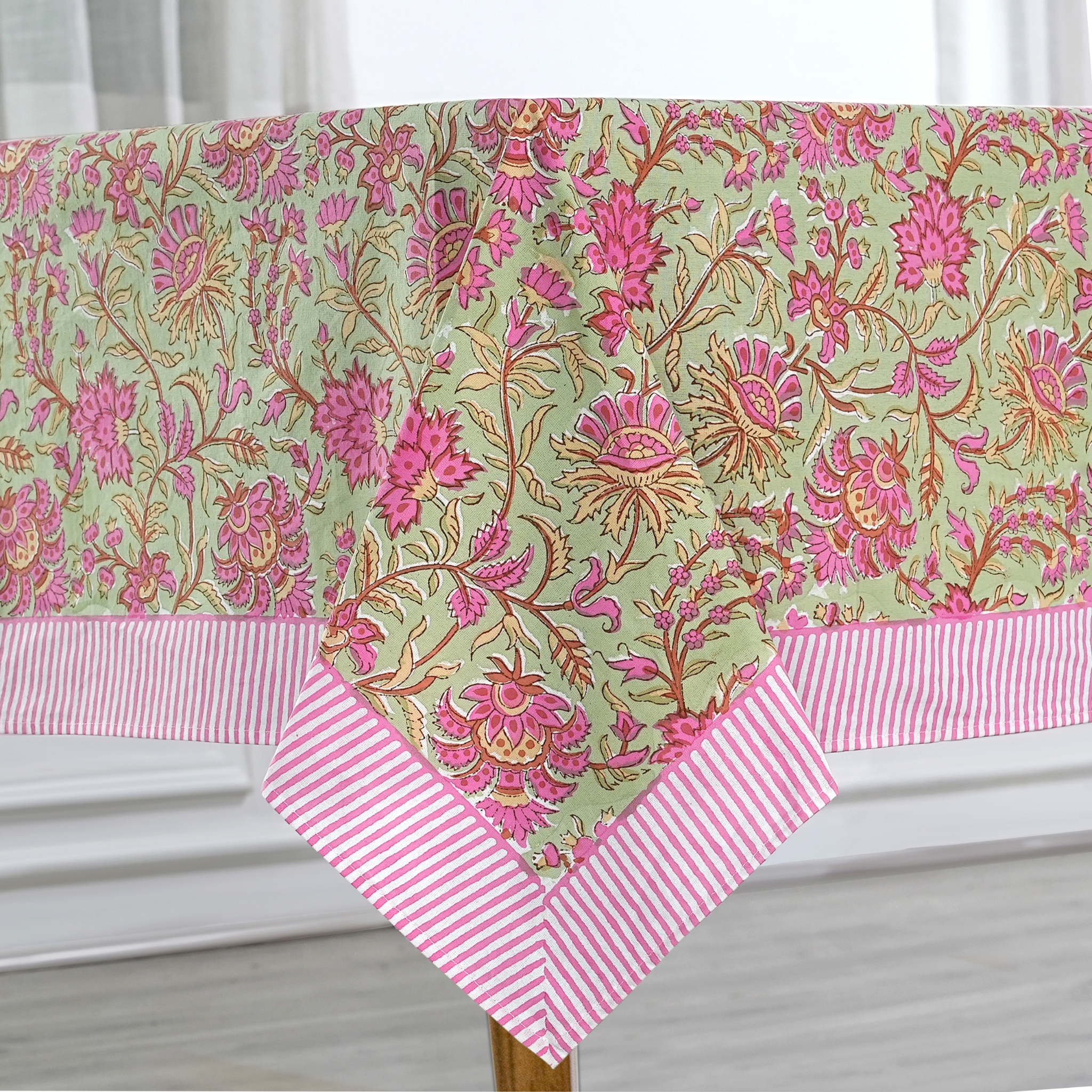 Floral tablecloth with pink and white striped border on a white surface