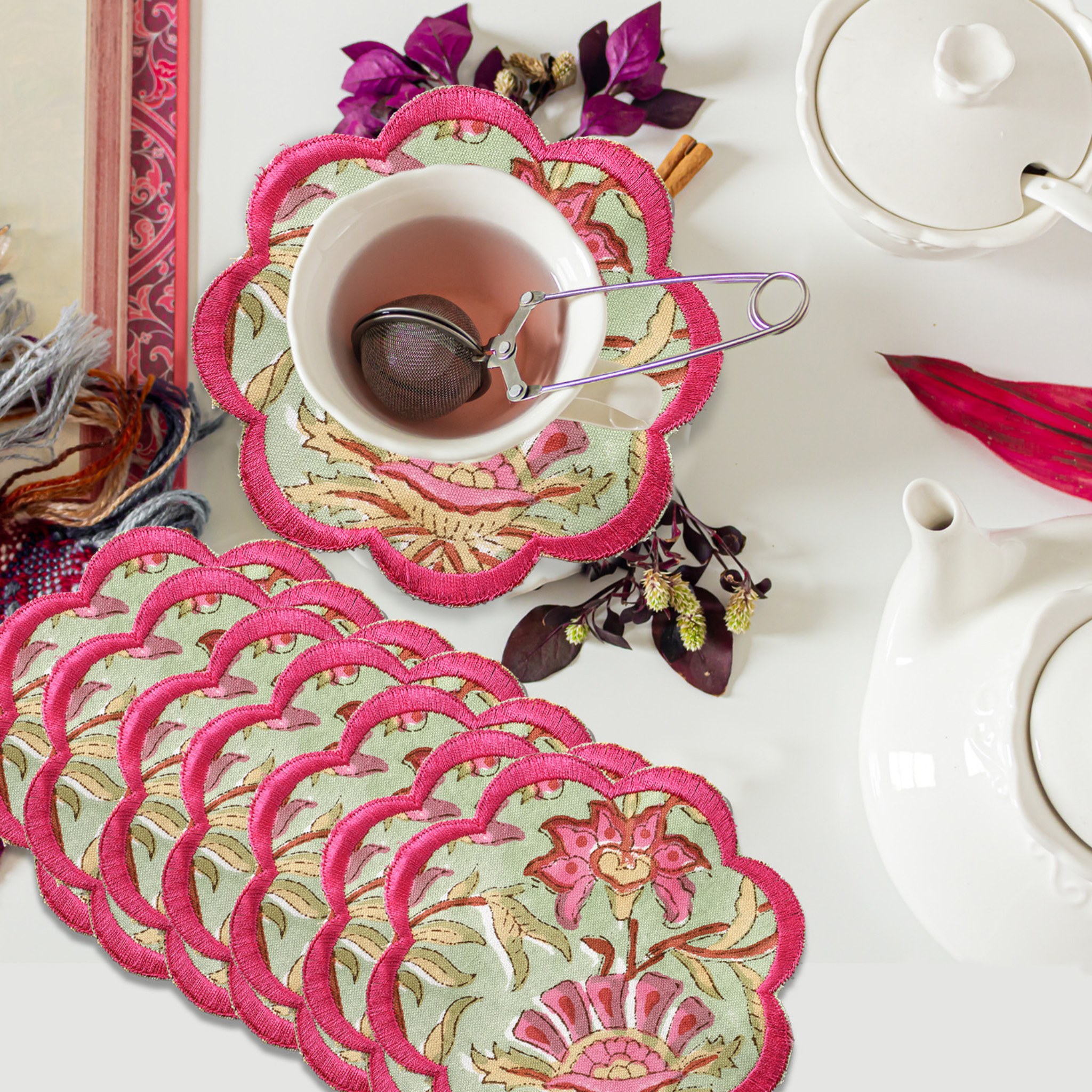 Set of floral coasters with pink trim on a table with tea set