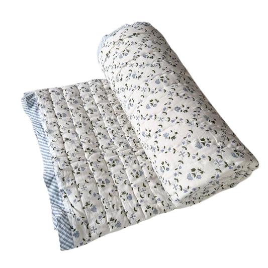 Floral-patterned quilt and pillow on a white background