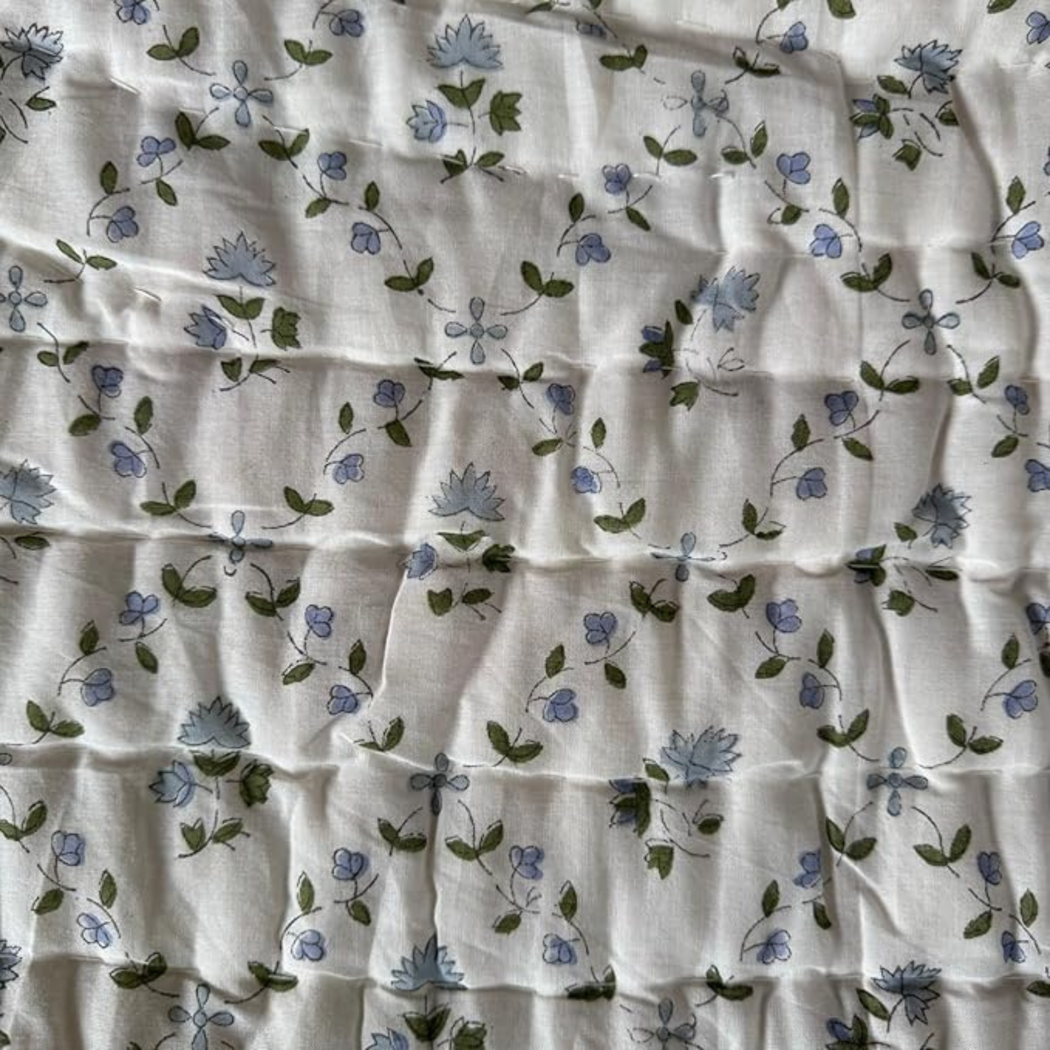 Floral patterned fabric with blue flowers and green leaves on a white background