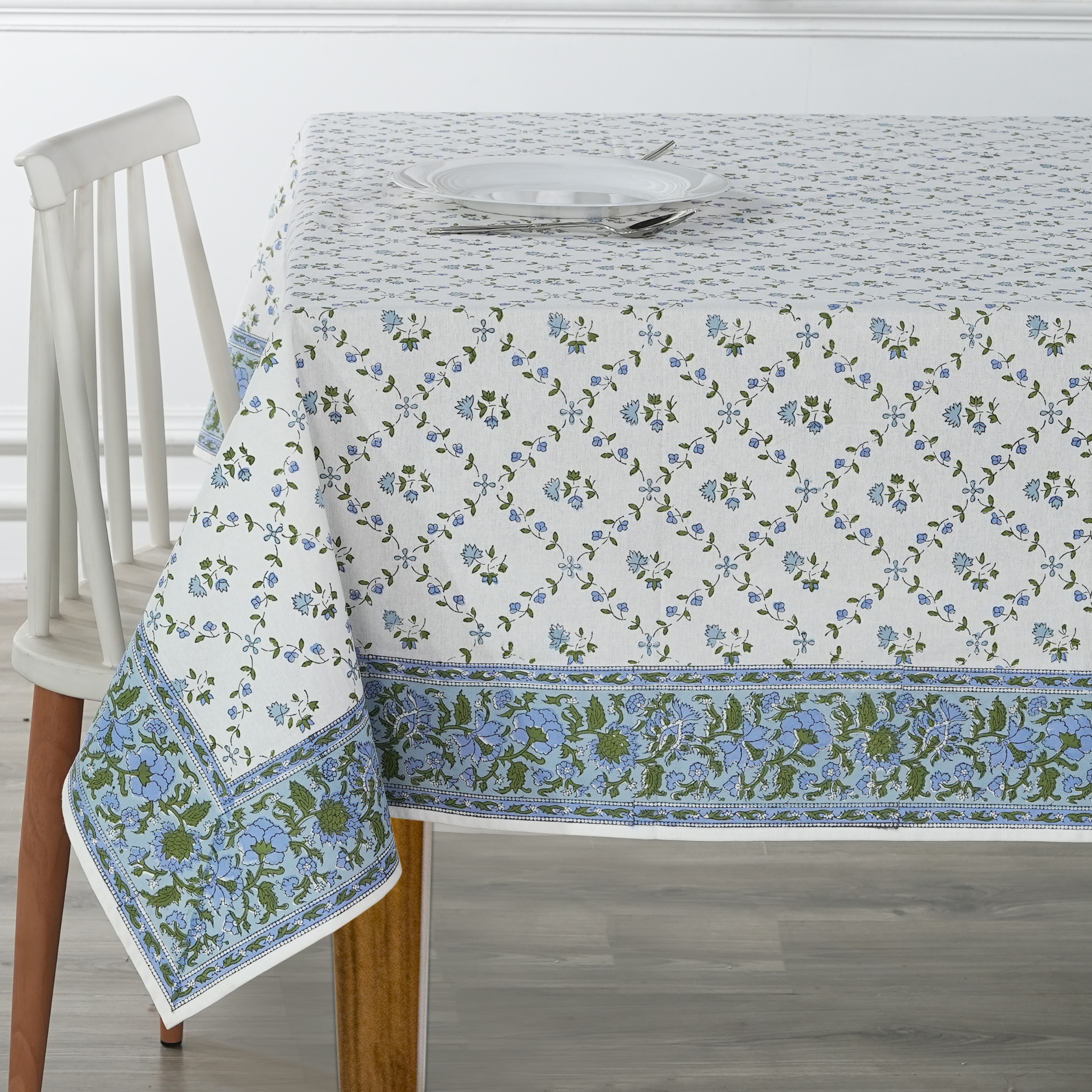 Tablecloth with floral pattern on a wooden table and chair.