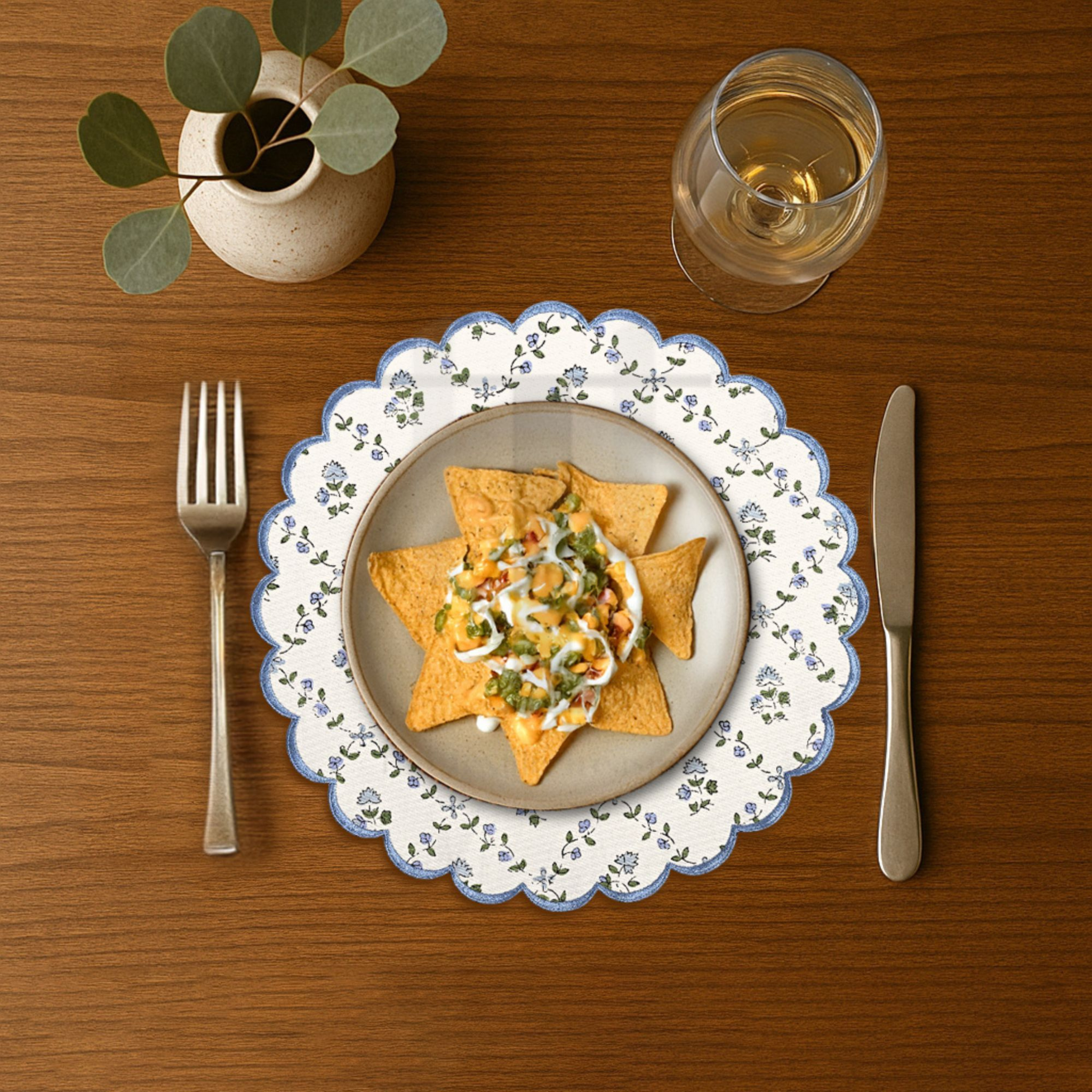 Dinner setting with a plate of food, fork, knife, and glass on a wooden table.